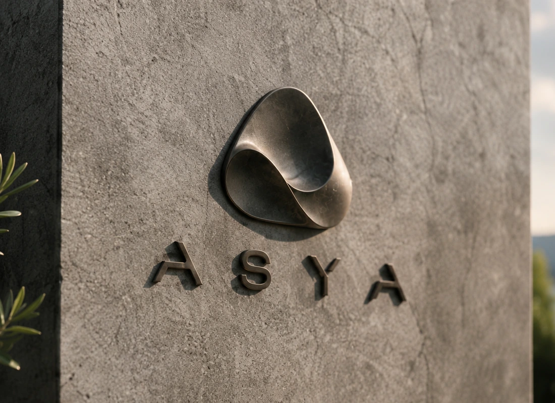 The ASYA symbol and name mounted on a stone wall, olive leaves in the foreground.
